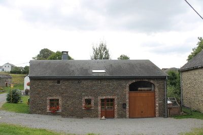 La grange en pierre avec les portes du garage.