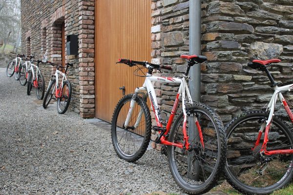 Des VTT appuyés contre le mur en pierre, à côté de la porte du garage.